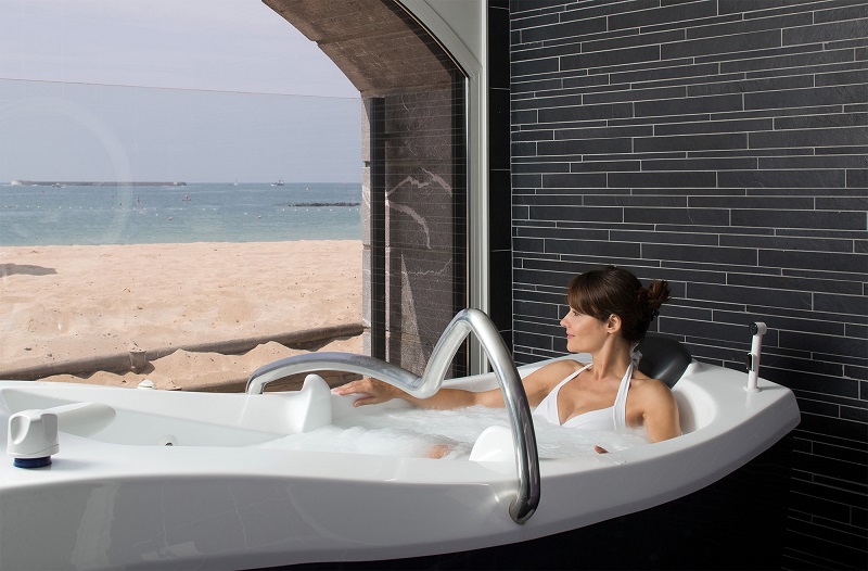 Mujer dándose un baño en hotel de lujo frente al mar en un spa