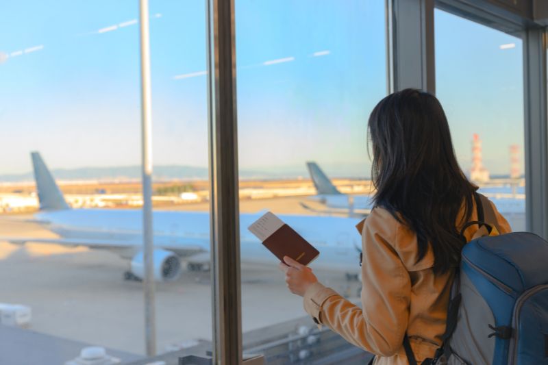 Mujer con pasaporte mirando un avión
